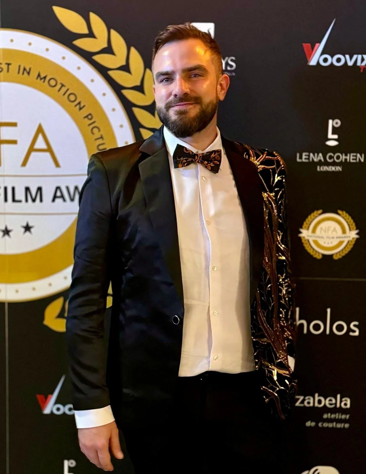 A man in a suit standing against a black and yellow background