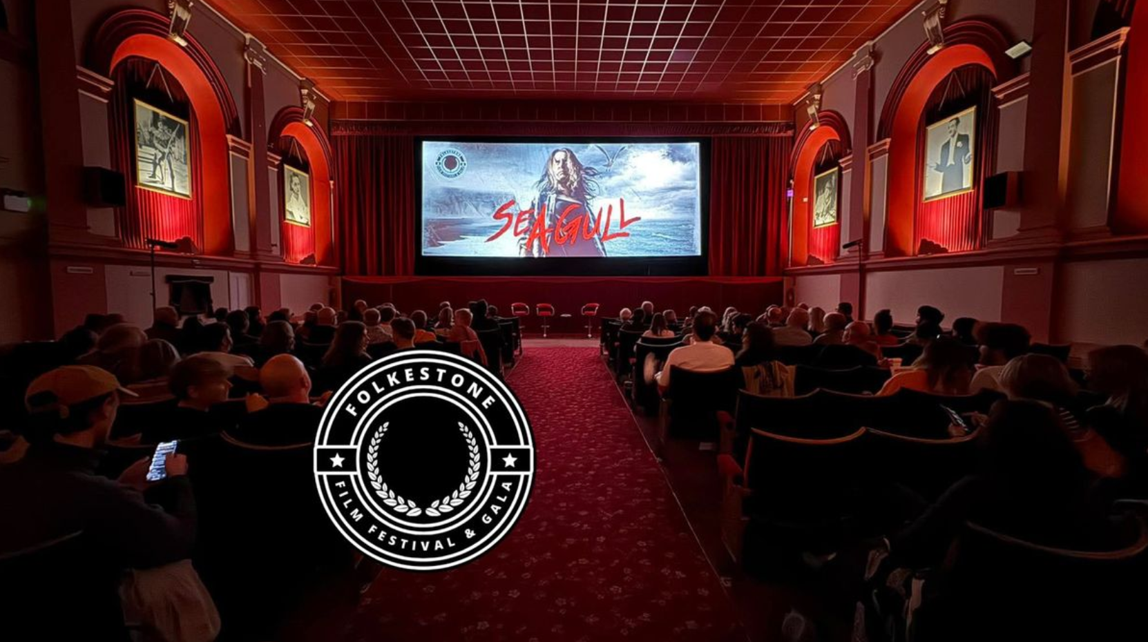 A cinema with people in the seats watching the large screen