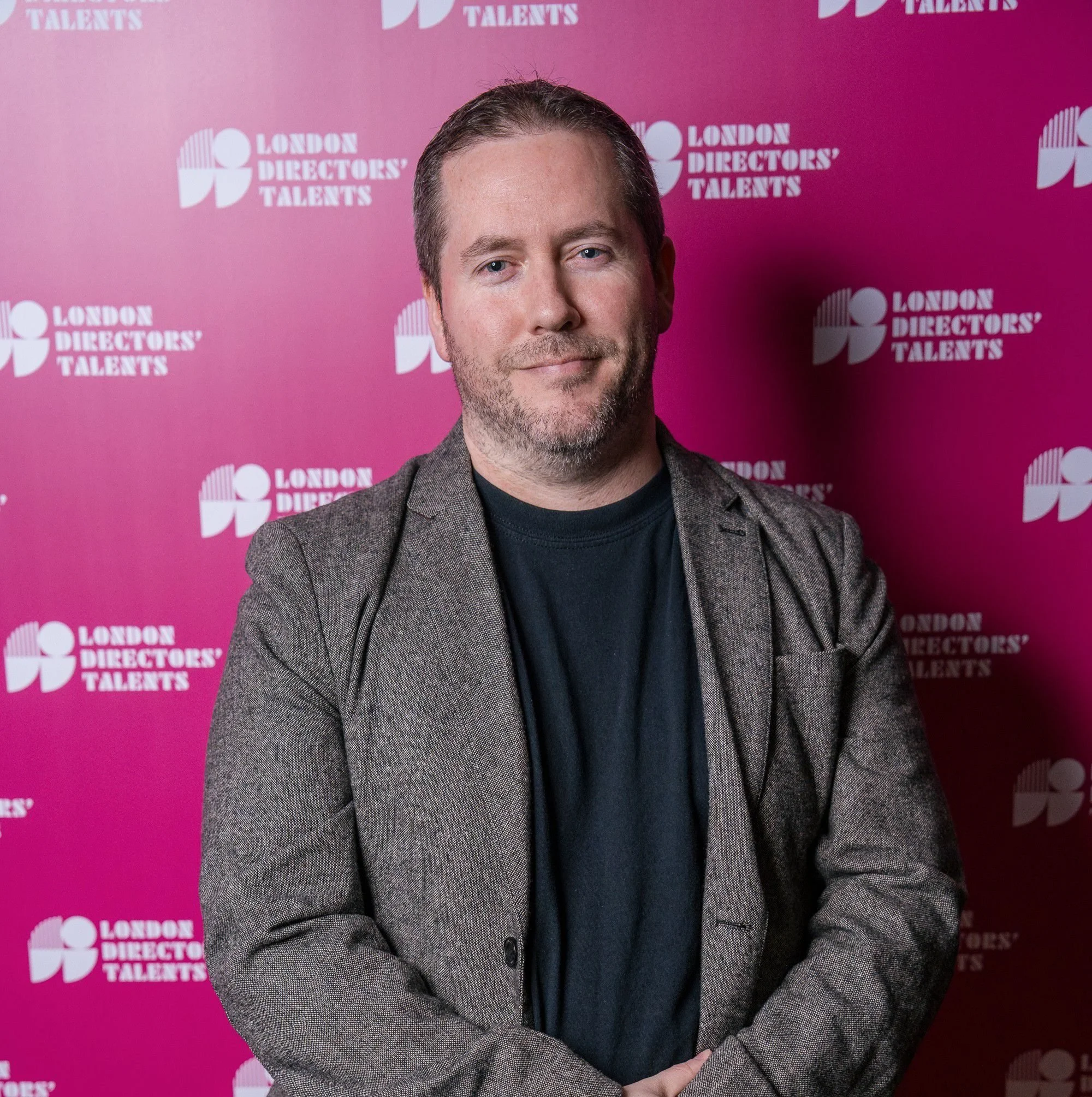 Man standing against a pink backdrop