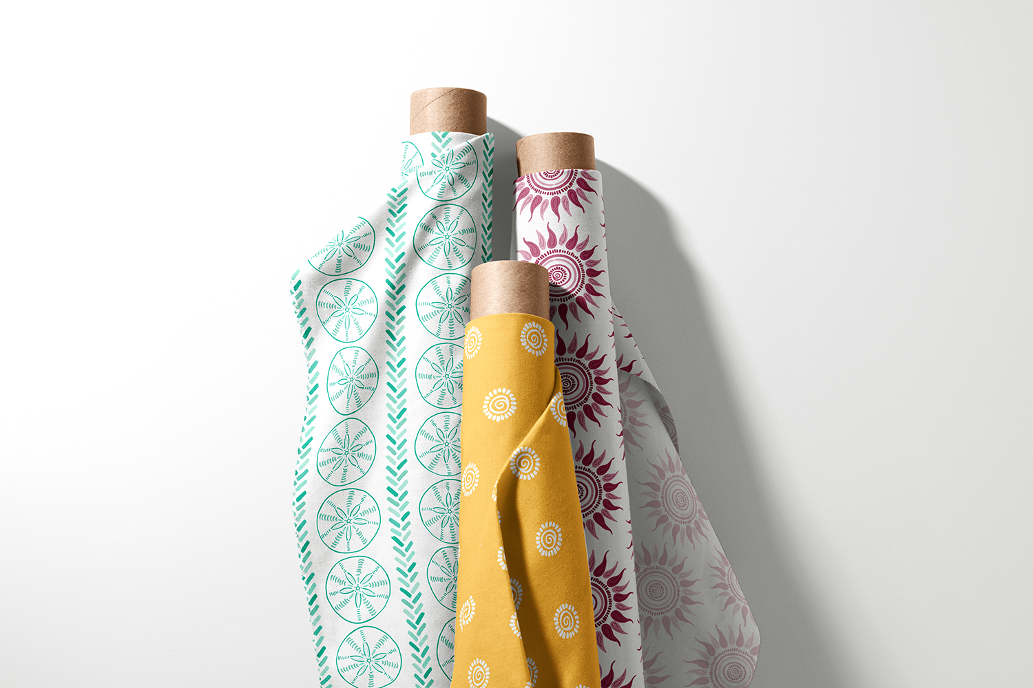 Three rolls of sand dollar, spiral sun, and sunburst fabric from the Coastal Summer collection by Sue Ivy Designs