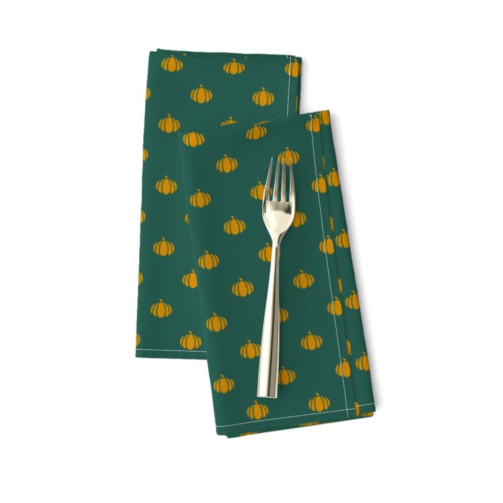 Gold block print pumpkins on dark teal napkins for a fall table setting.