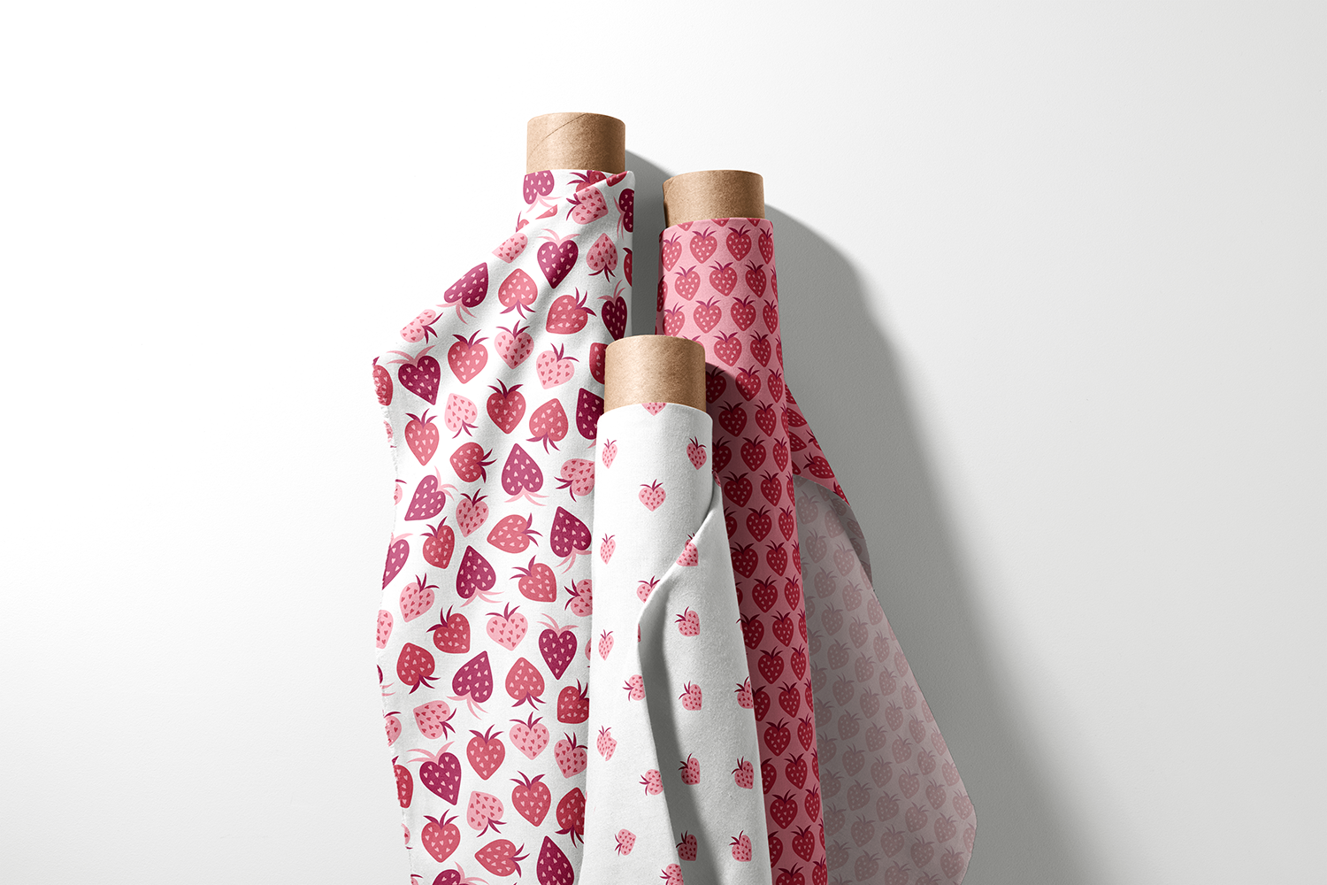 Three rolls of heart-shaped strawberry fabric in pink and berry tones from the Fruitful Hearts collection by Sue Ivy Designs