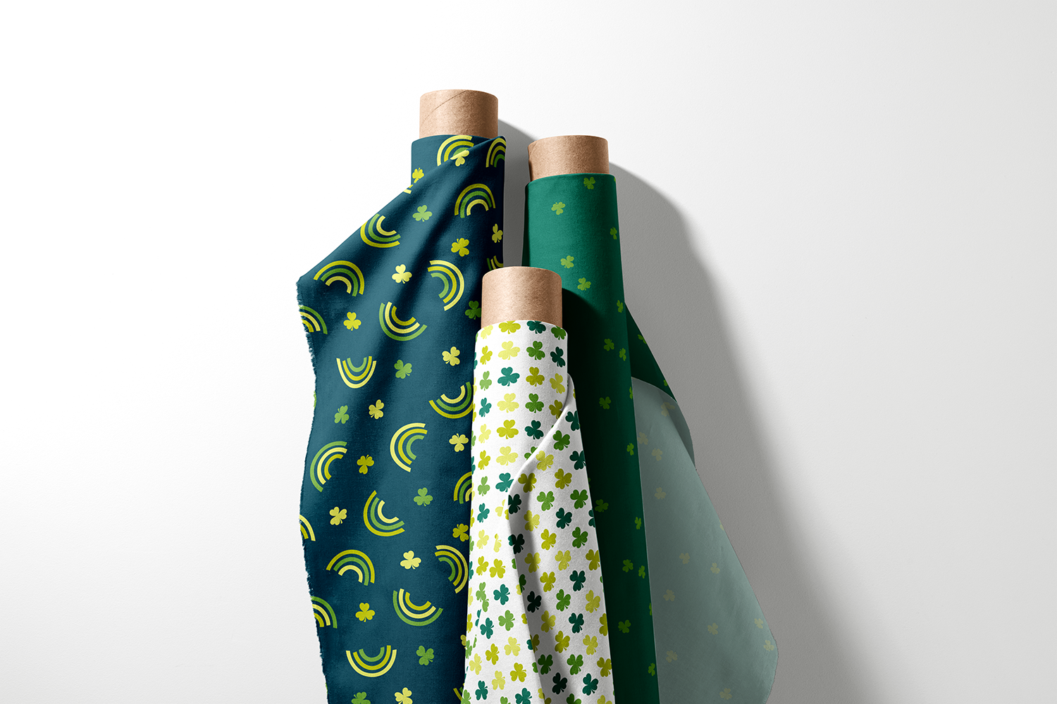 Three rolls of rainbow, shamrock, and tonal clover fabric from the Lucky Rainbows collection by Sue Ivy Designs