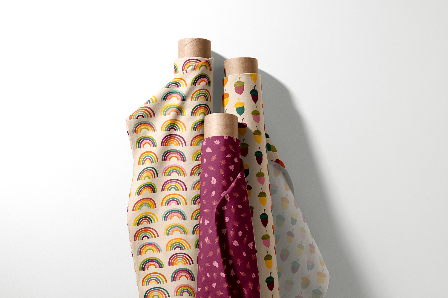 Three rolls of rainbow, fall leaf, and acorn fabric from the Autumn Rainbows collection by Sue Ivy Designs