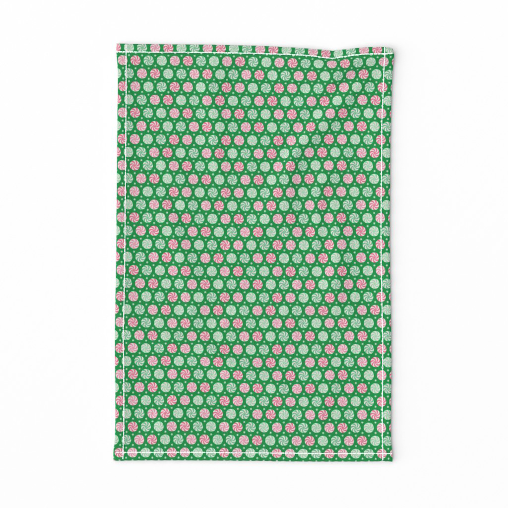 Tea towel in pink and mint peppermint swirls and snowflakes on bright green.