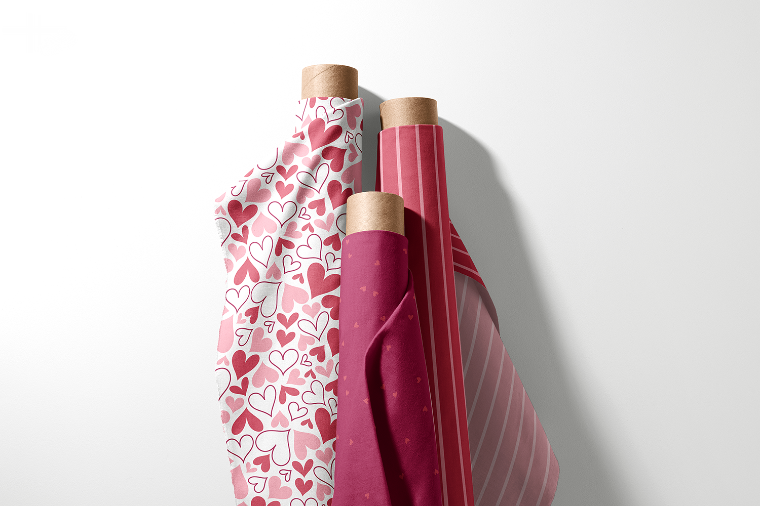 Three rolls of tossed heart, tonal heart, and stripe fabric from the Playful Hearts collection by Sue Ivy Designs