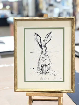 A framed sketch of a rabbit with long ears on a small easel, displayed outdoors.
 custom framing brookline pictureplacebrookline.com