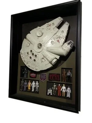 A framed display of the Millennium Falcon from Star Wars, along with figurines and memorabilia related to the Star Wars universe  custom framing brookline pictureplacebrookline.com.