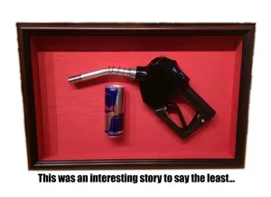 Framed display featuring a gas pump, a Red Bull energy drink can with a caption reading 'This was an interesting story to say the least...  custom framing brookline pictureplacebrookline.com