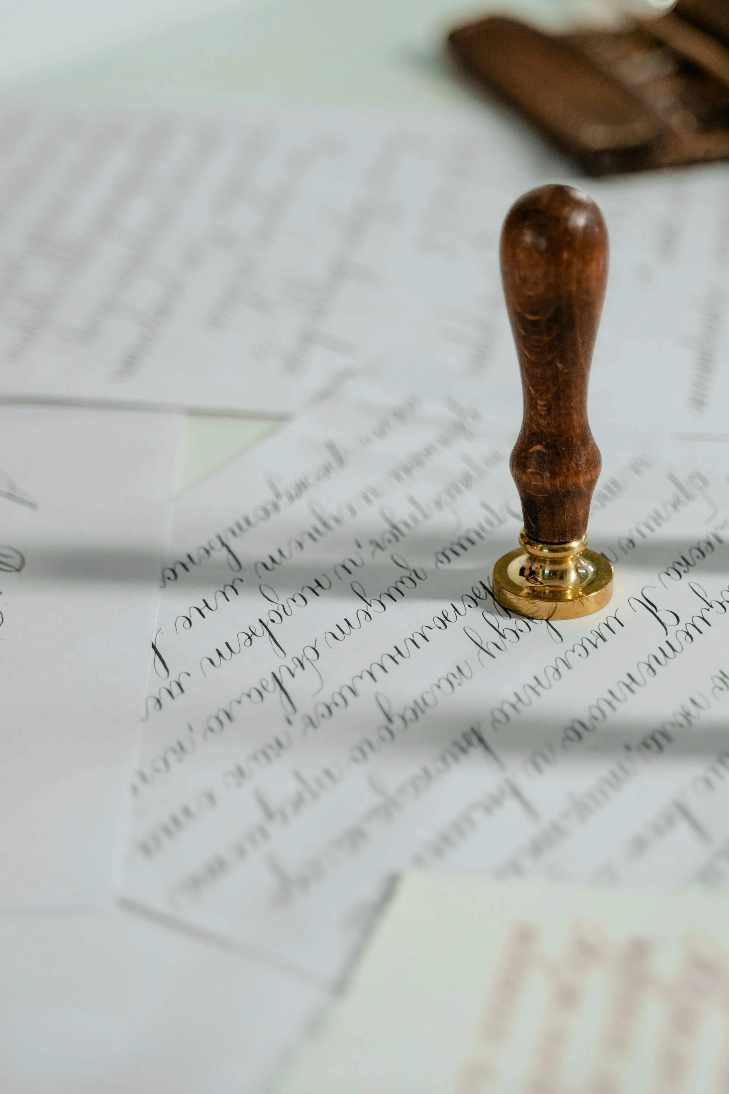 Close-up of a partially visible handwritten letter with a wooden stamp placed on top of the paper.