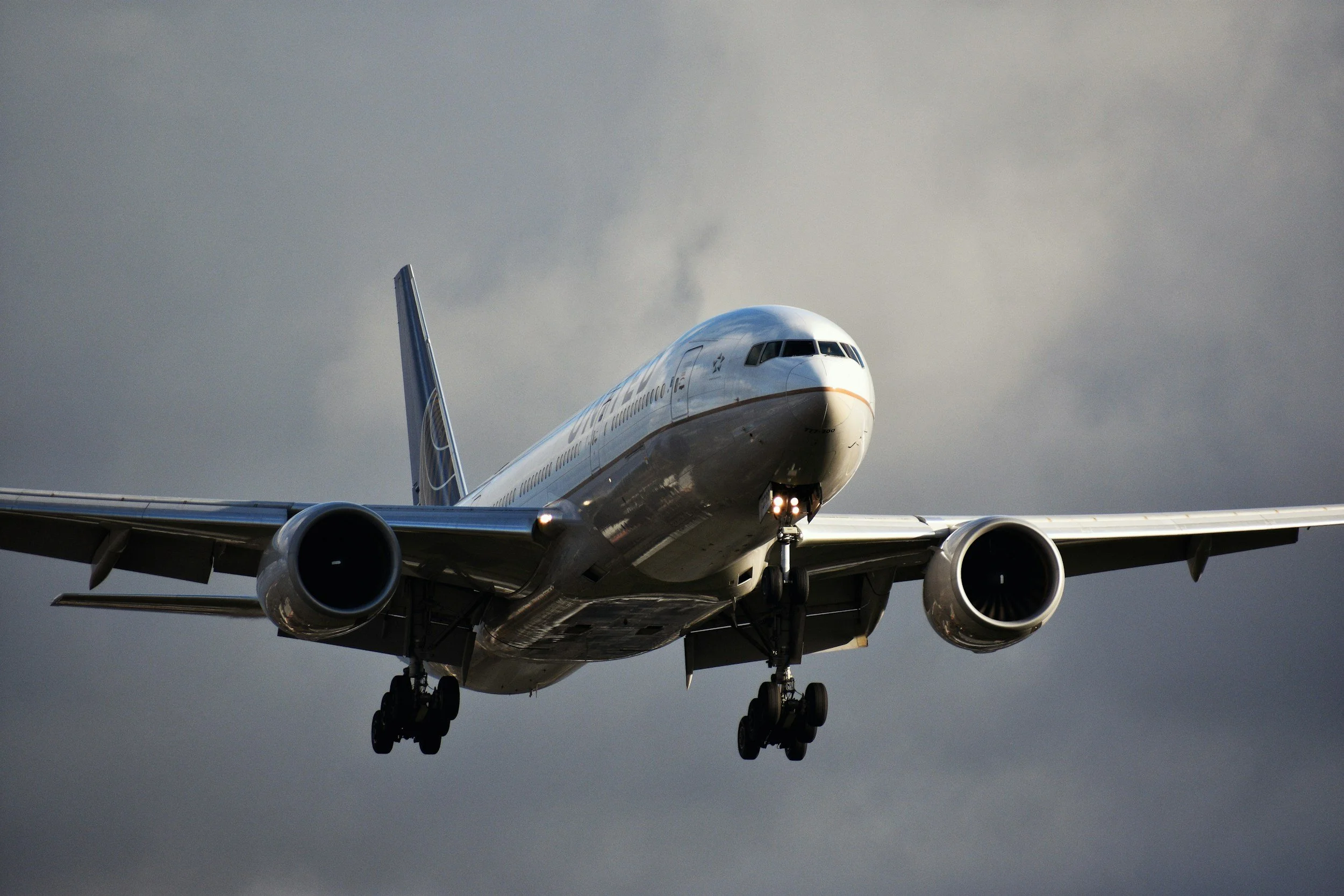 A commercial airplane flying through a cloudy sky, viewed from below.