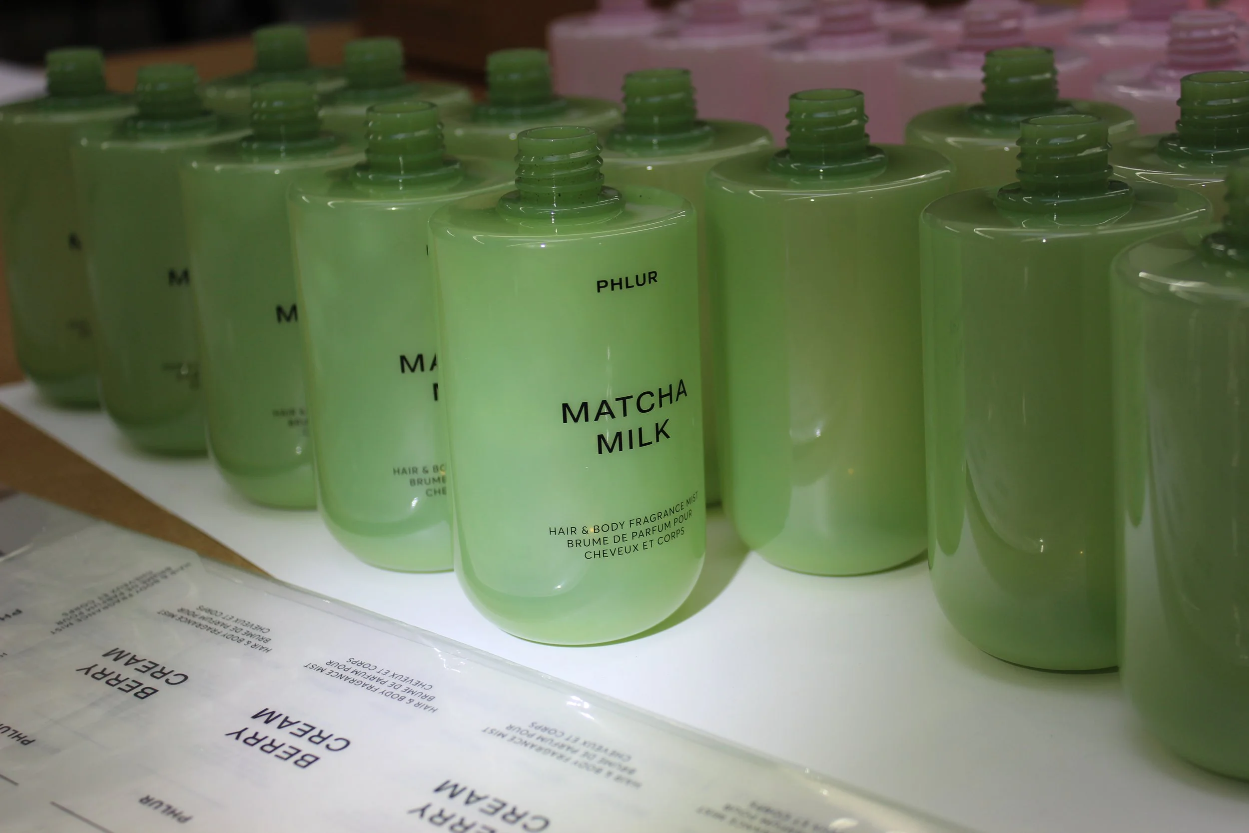 Close-up of multiple green bottles labeled 'Matcha Milk' on a surface with documents underneath.