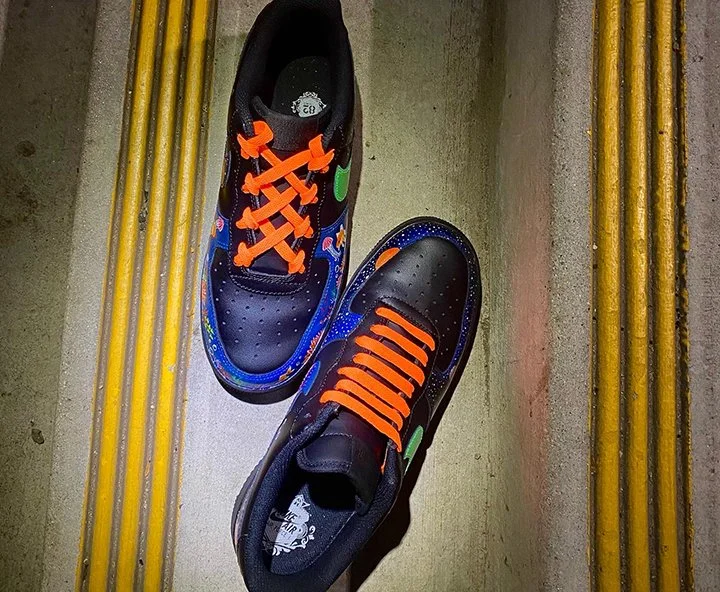 Colorful sneakers with neon green, orange, and blue accents on a gray concrete floor with yellow lines.