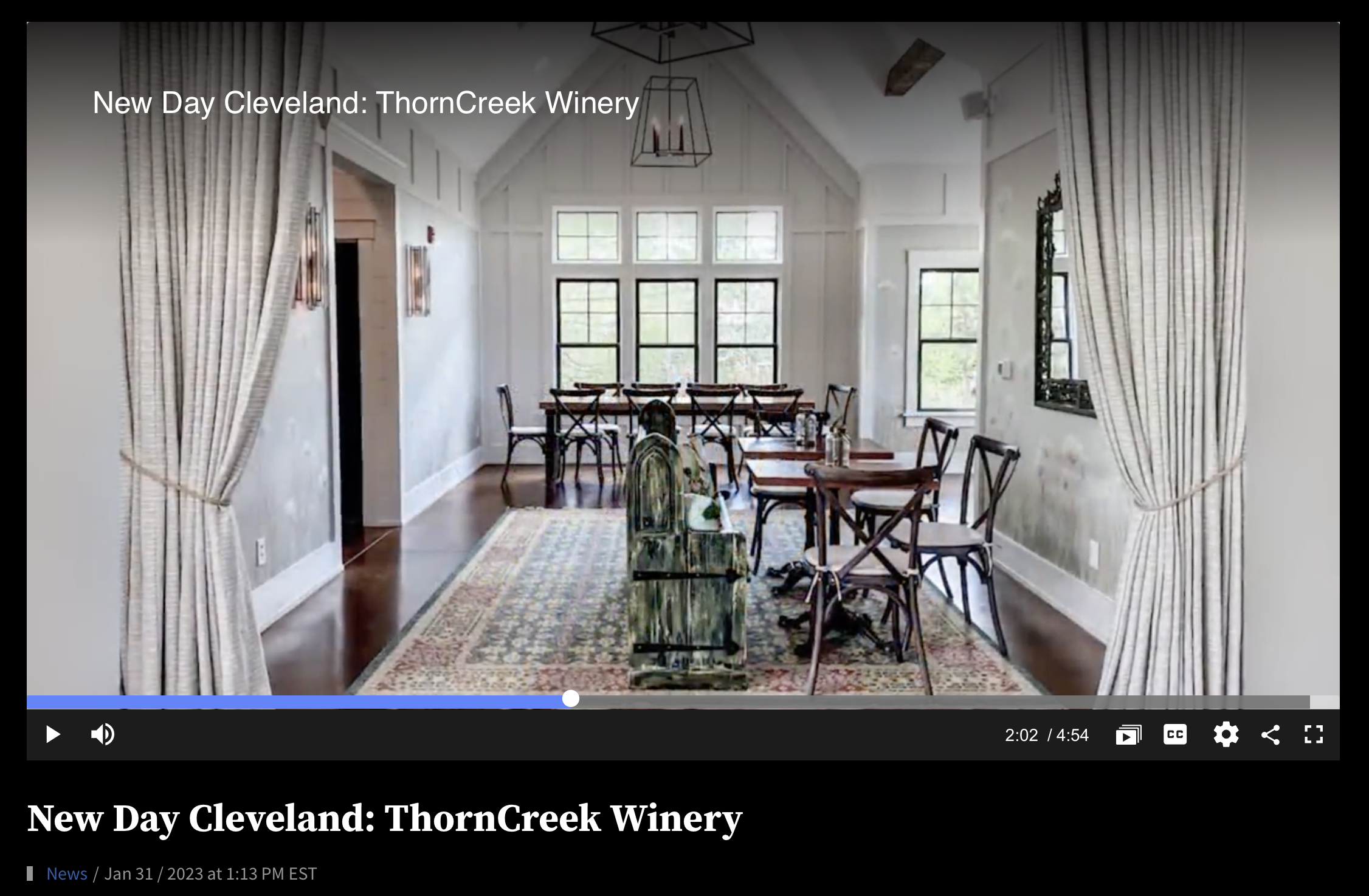 Interior view of a dining room at ThornCreek Winery in Cleveland, featuring a high ceiling, large windows, a long dining table with multiple chairs, a decorative area rug, and curtains on the sides.