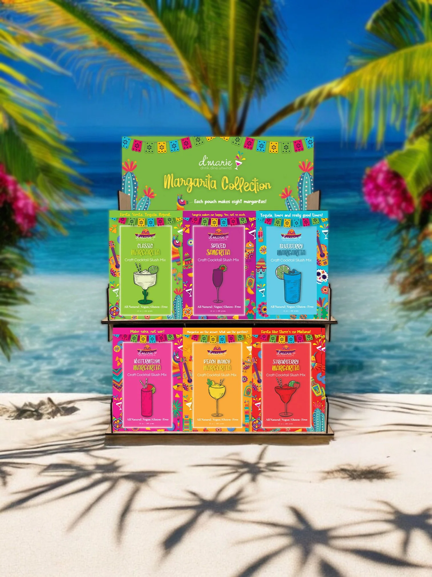Colorful Margarita Collection display with six different craft cocktail slush mixes on a hanging stand at the beach, with palm trees and ocean background.