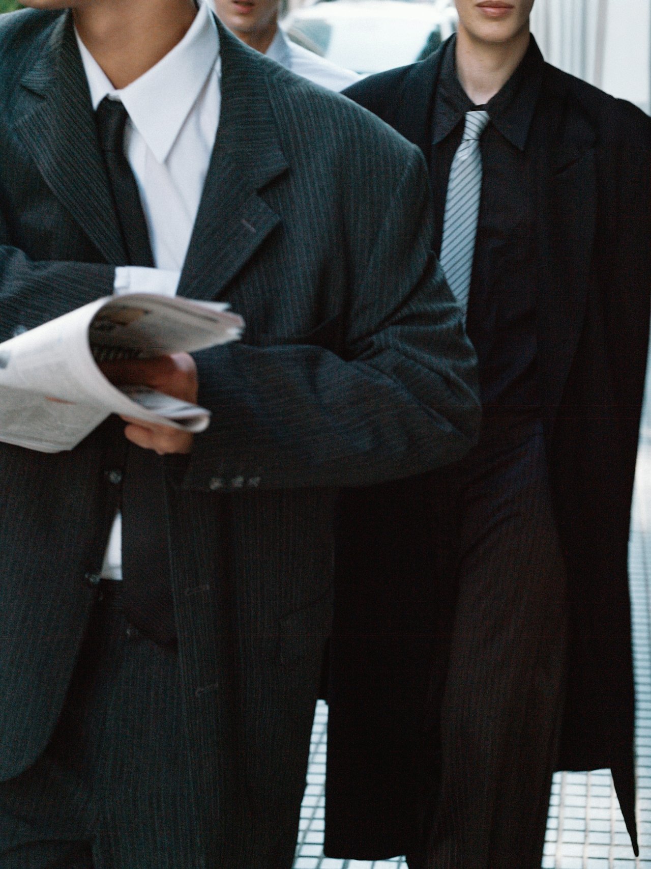 Close-up of two people in formal business suits standing together, with one person holding a notebook or folder.