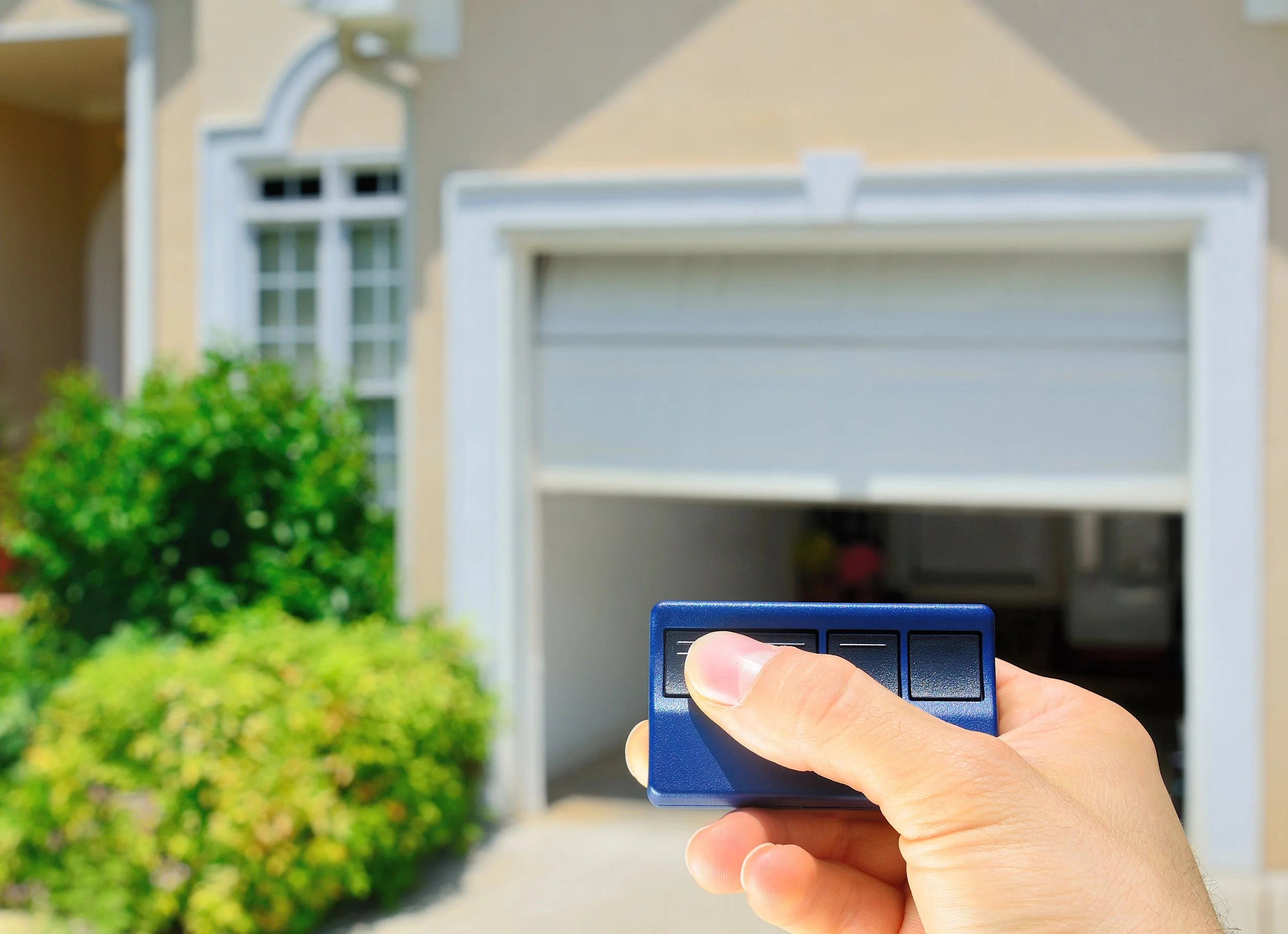 Person holding a remote control in front of a garage door.