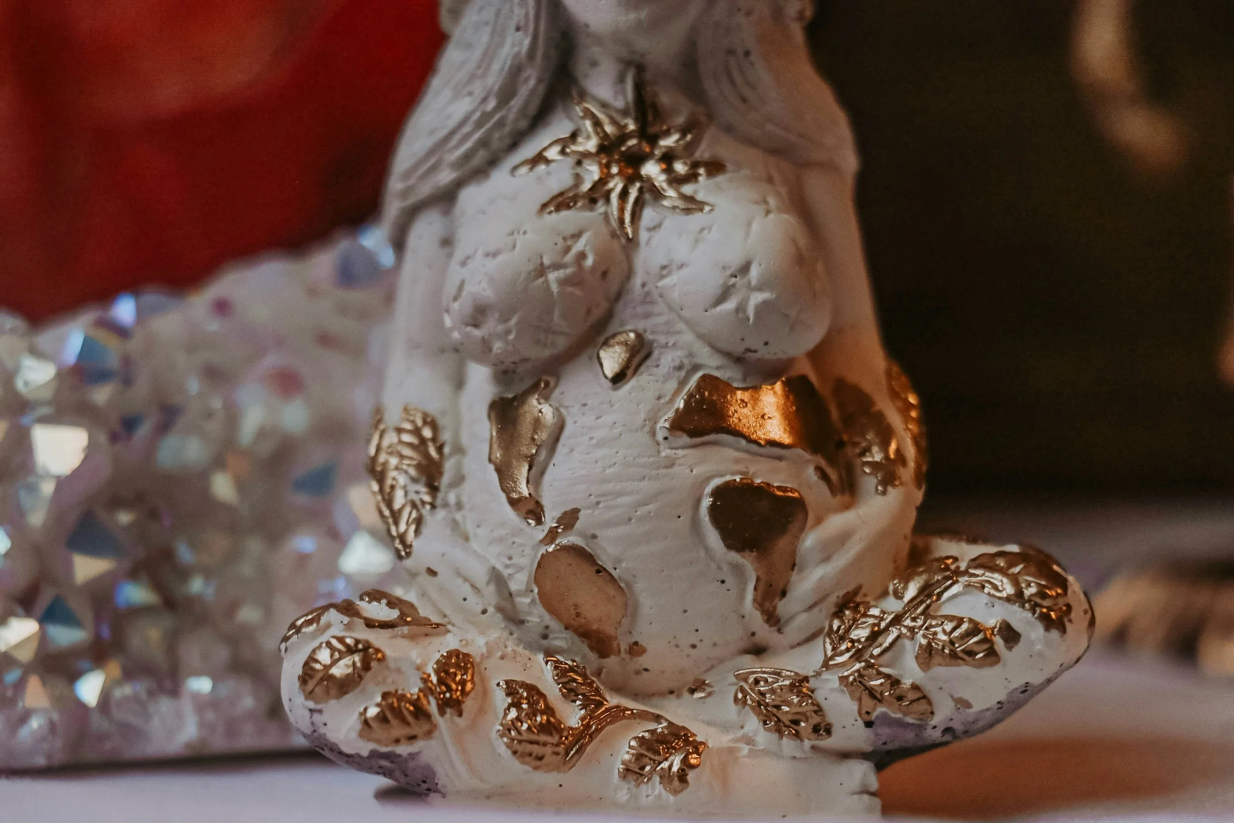 A close-up image of a sculpture of a pregnant woman, featuring a gold star and intricate decorations.