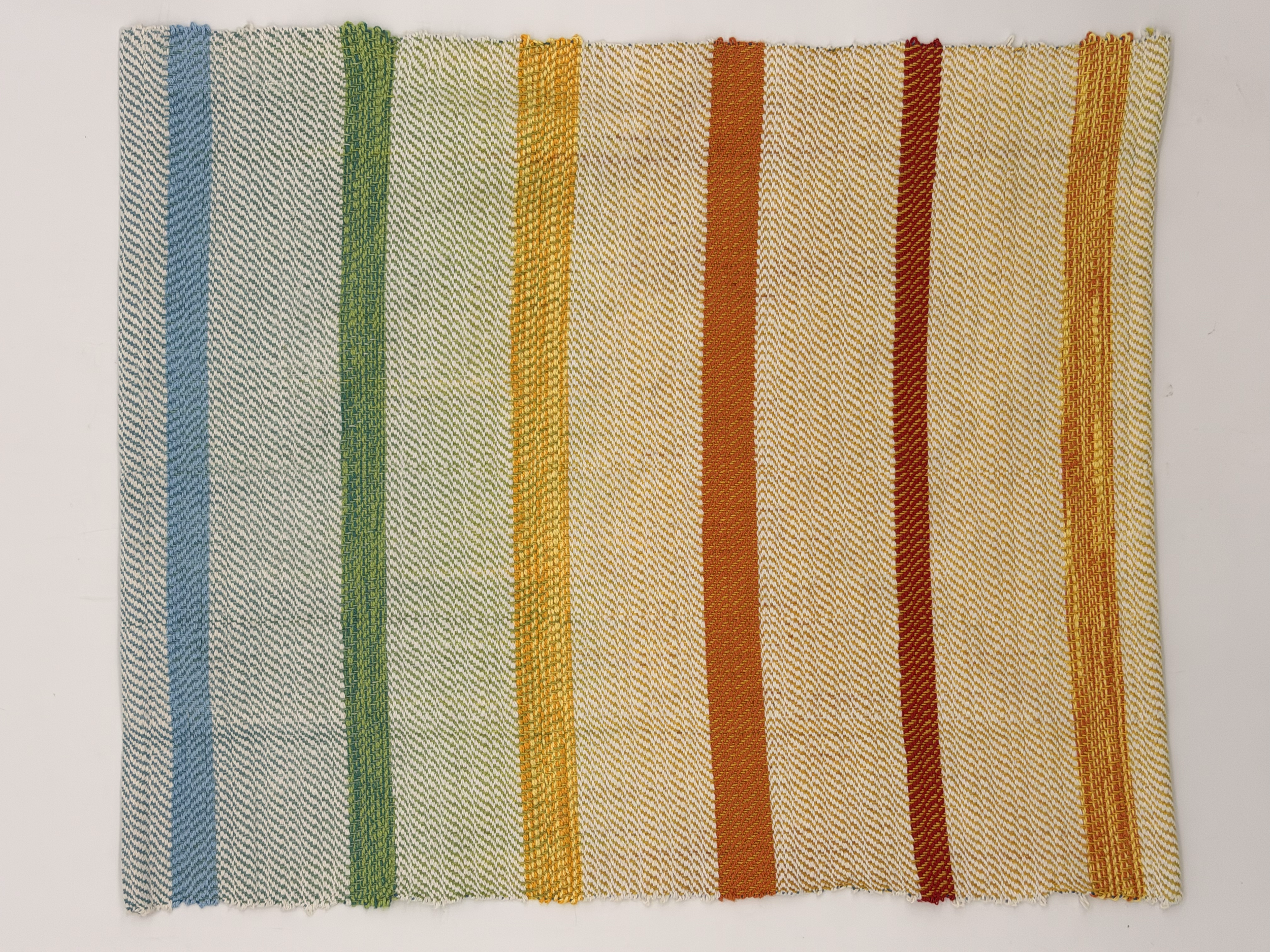 Colorful woven fabric with vertical stripes in blue, green, yellow, orange, red, and yellow, displayed against a white background.