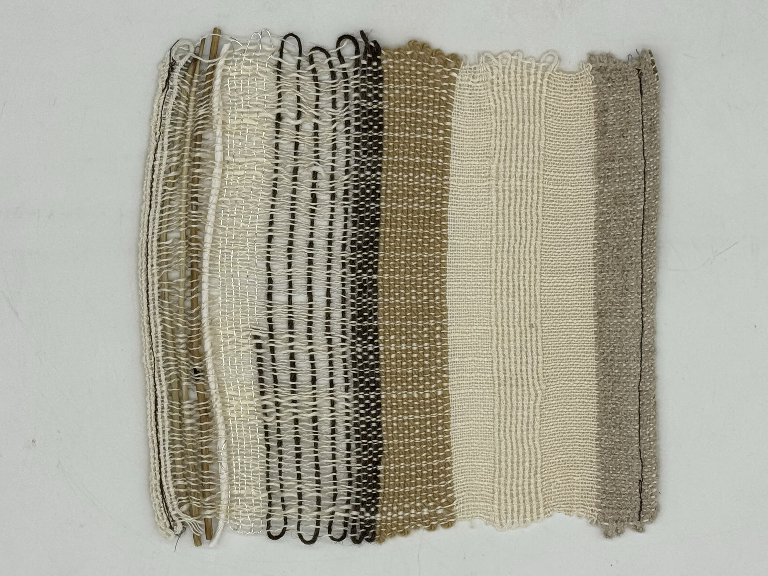 Six woven textile samples in neutral tones hanging on a white wall, showcasing different weaving patterns and textures.