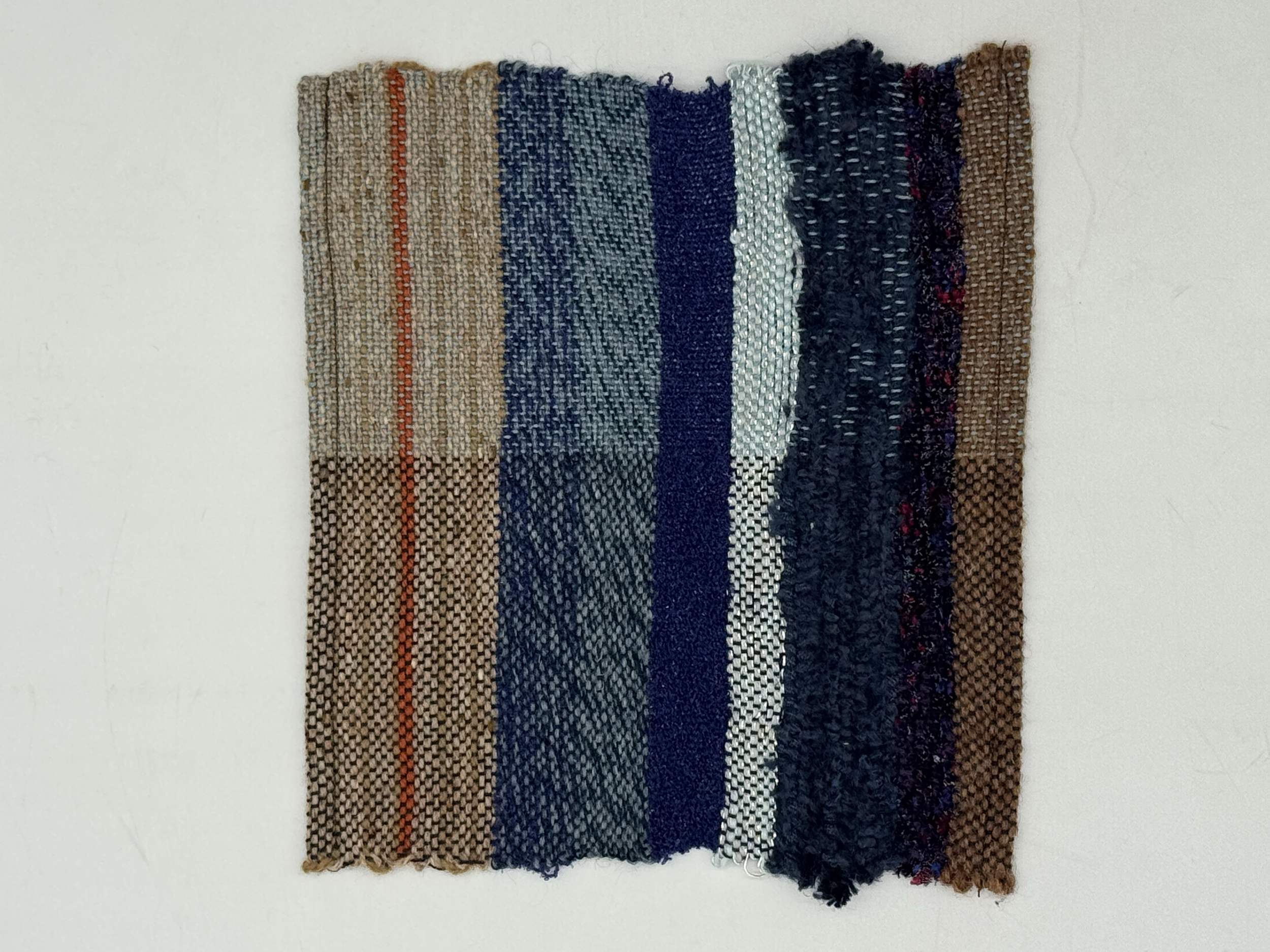 A woven textile in various shades of brown, blue, white, and black with different patterns and textures.