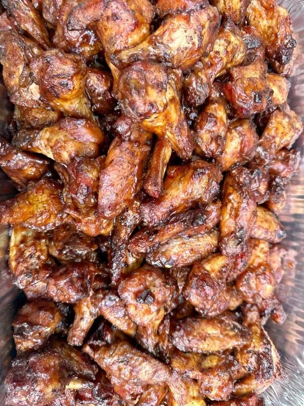 Close-up of cooked, glazed chicken pieces in a glass dish.