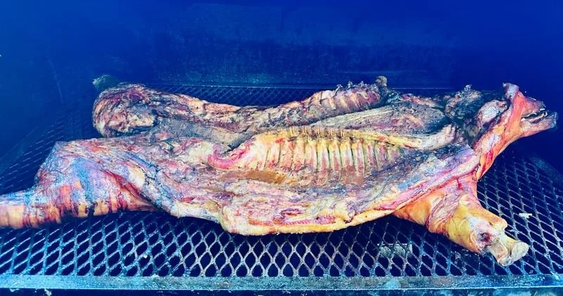 Large fish being cooked on a grill, with its ribs and bones visible.