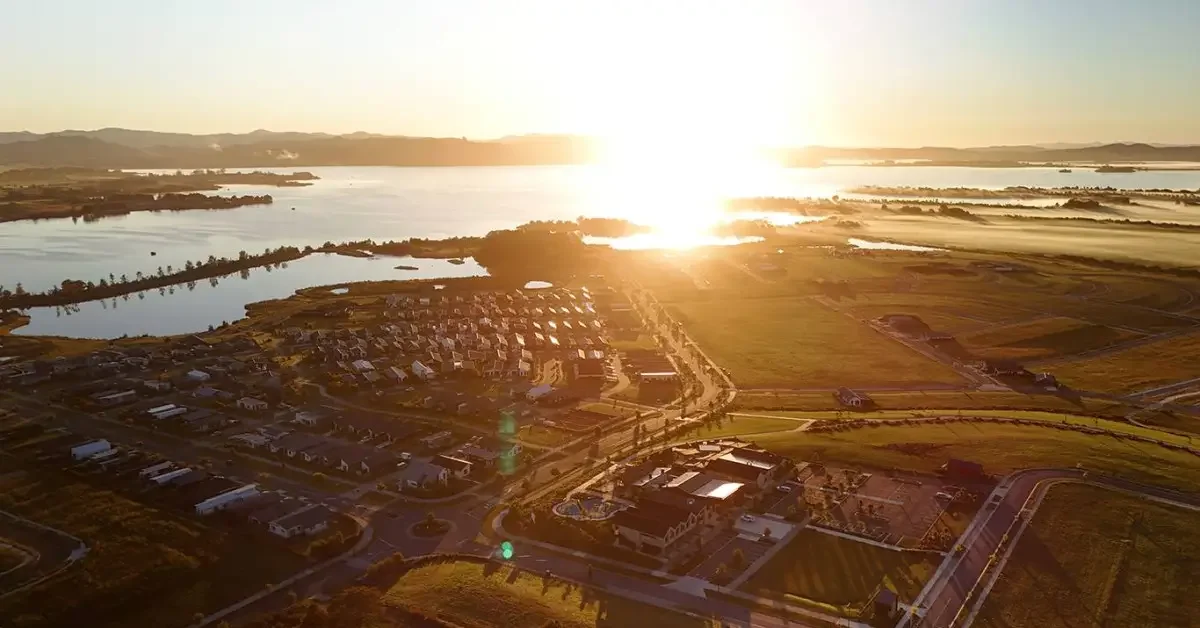 Aerial view of a suburban community near a large water body during sunset.
