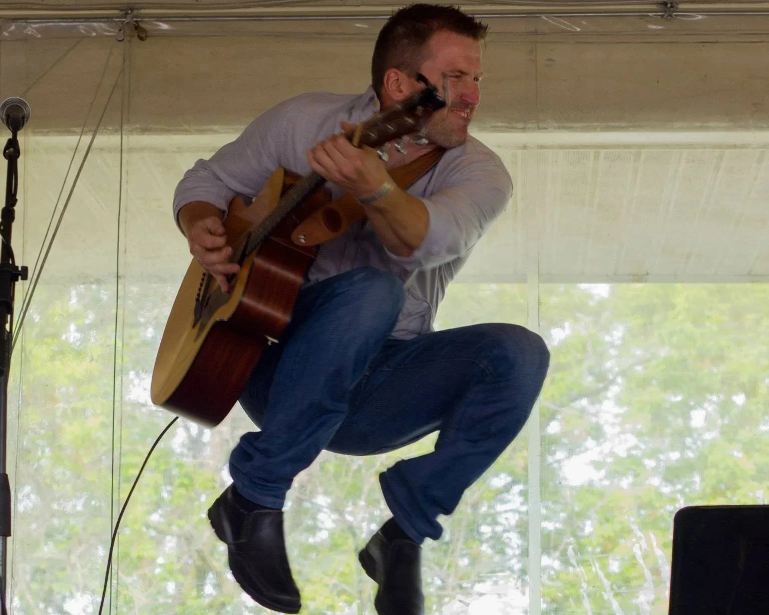 Matt jumping on stage with an acoustic guitar