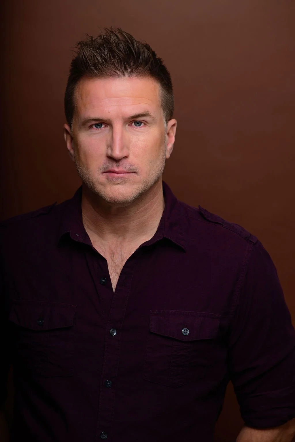 Matt Specht Headshot - serious face, dark button up shirt, dark background