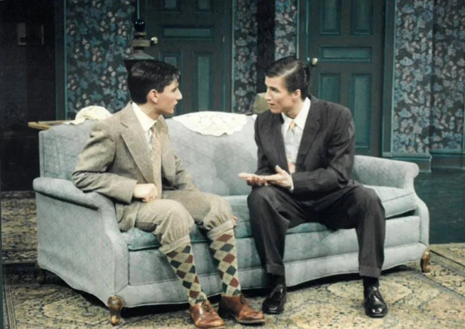Matt and another cast member sit on a couch 
