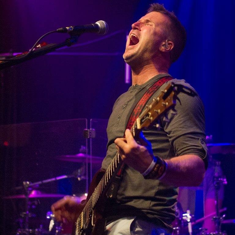 Matt on stage playing guitar and singing into a microphone