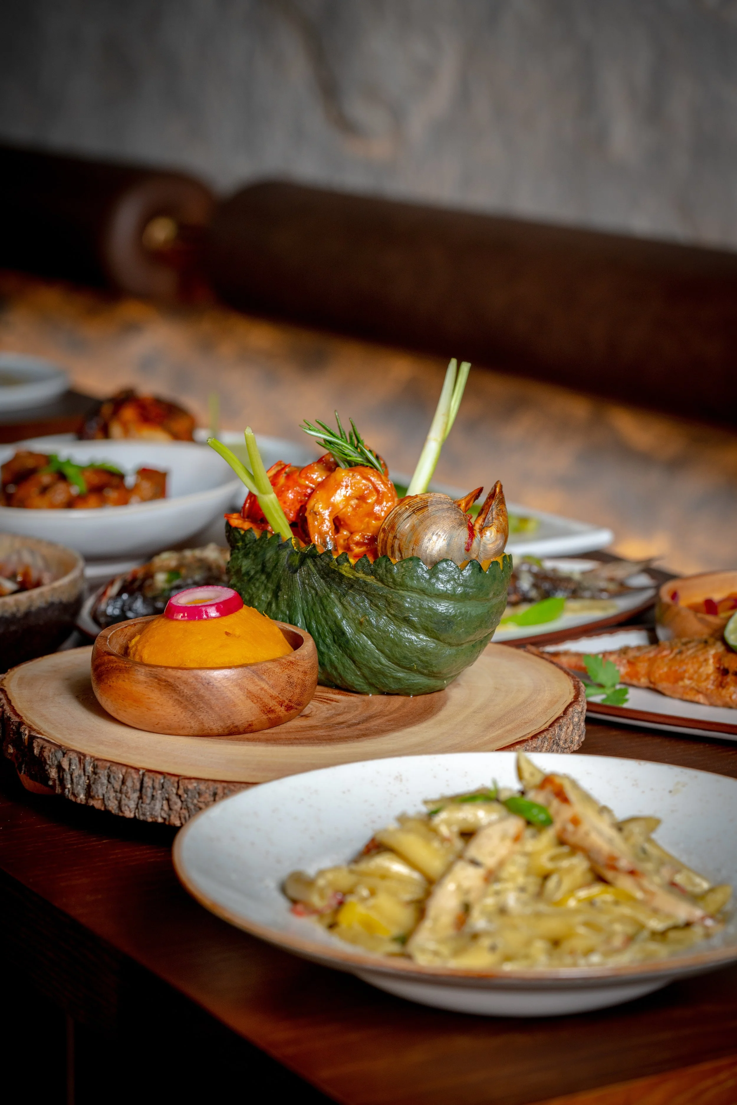 A variety of Caribbean dishes on a wooden table and several small bowls of other foods in the background.