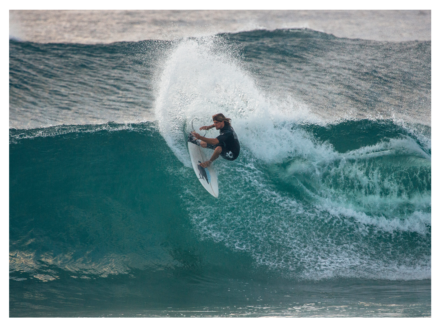 A person surfing on a large wave in the ocean.