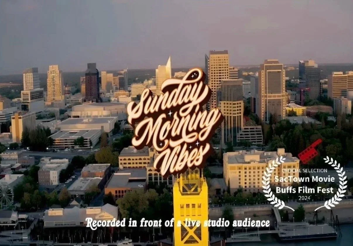 An aerial view of downtown Sacramento, California, with a prominent sign reading 'Sunday Morning Vibes' in the center. The image includes a yellow tower, a marina with boats, and a city skyline with tall buildings. There is also a laurel wreath with the text 'Official Selection SacTown Movie Buffs Film Fest 2024' and a red film reel icon, along with the caption 'Recorded in front of a live studio audience' at the bottom.