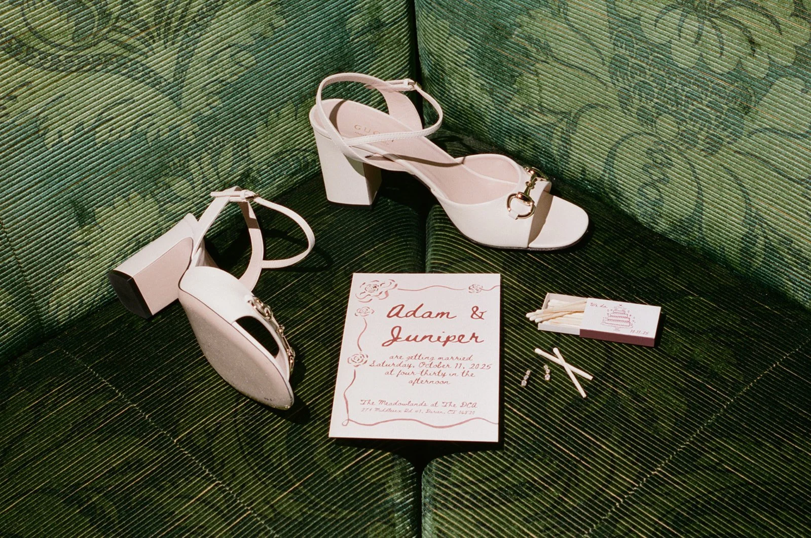Wedding invitation sitting next to a pack of matches and gucci shoes
