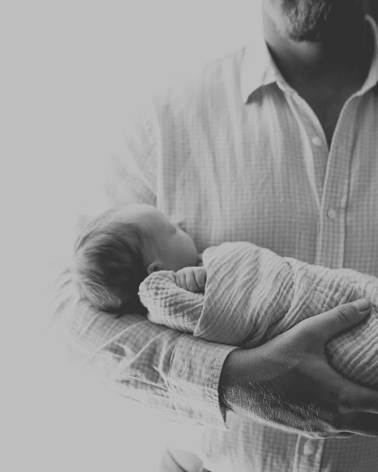 A man holding a newborn baby wrapped in a blanket.