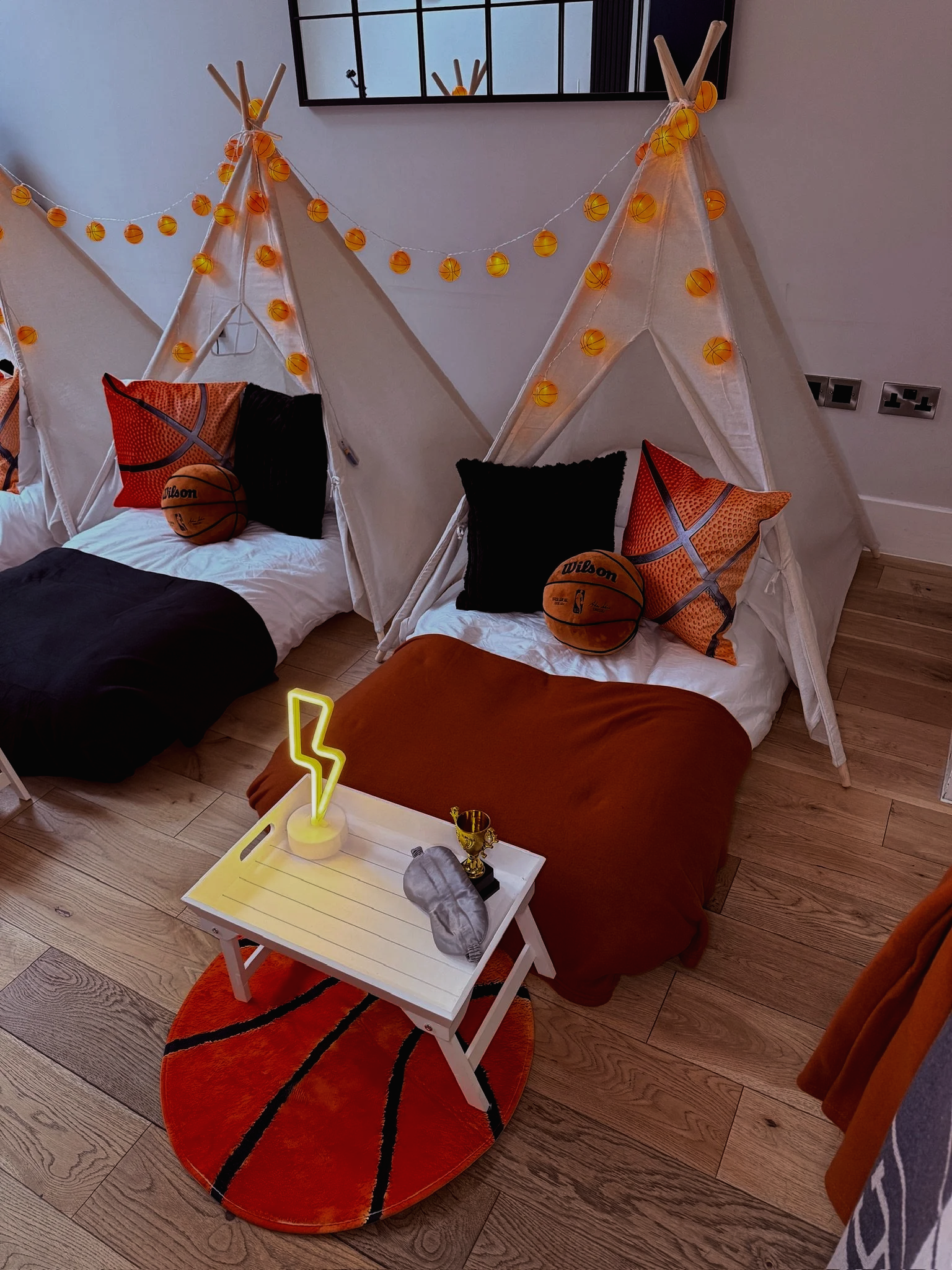 Basketball themed teepee sleepover party hire setup with orange fairy lights, basketball cushions and a gold trophy. Sweet Dreams Events Sussex Surrey Hampshire.