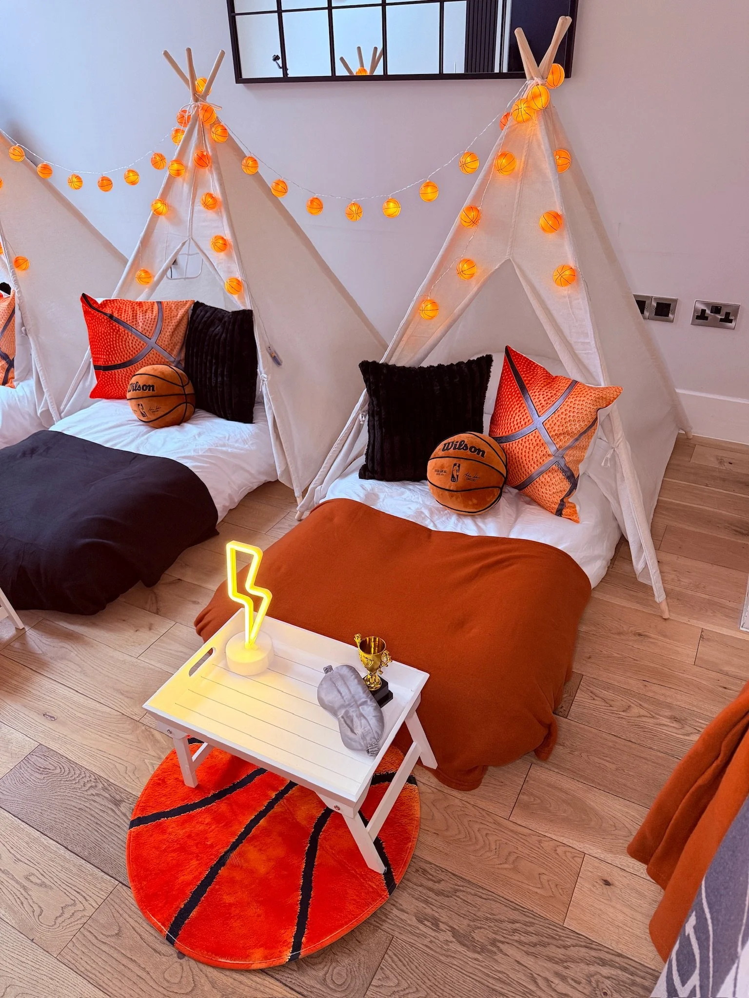 Basketball teepee sleepover party hire in Surrey with orange fairy lights, Wilson basketball cushions and basketball rug