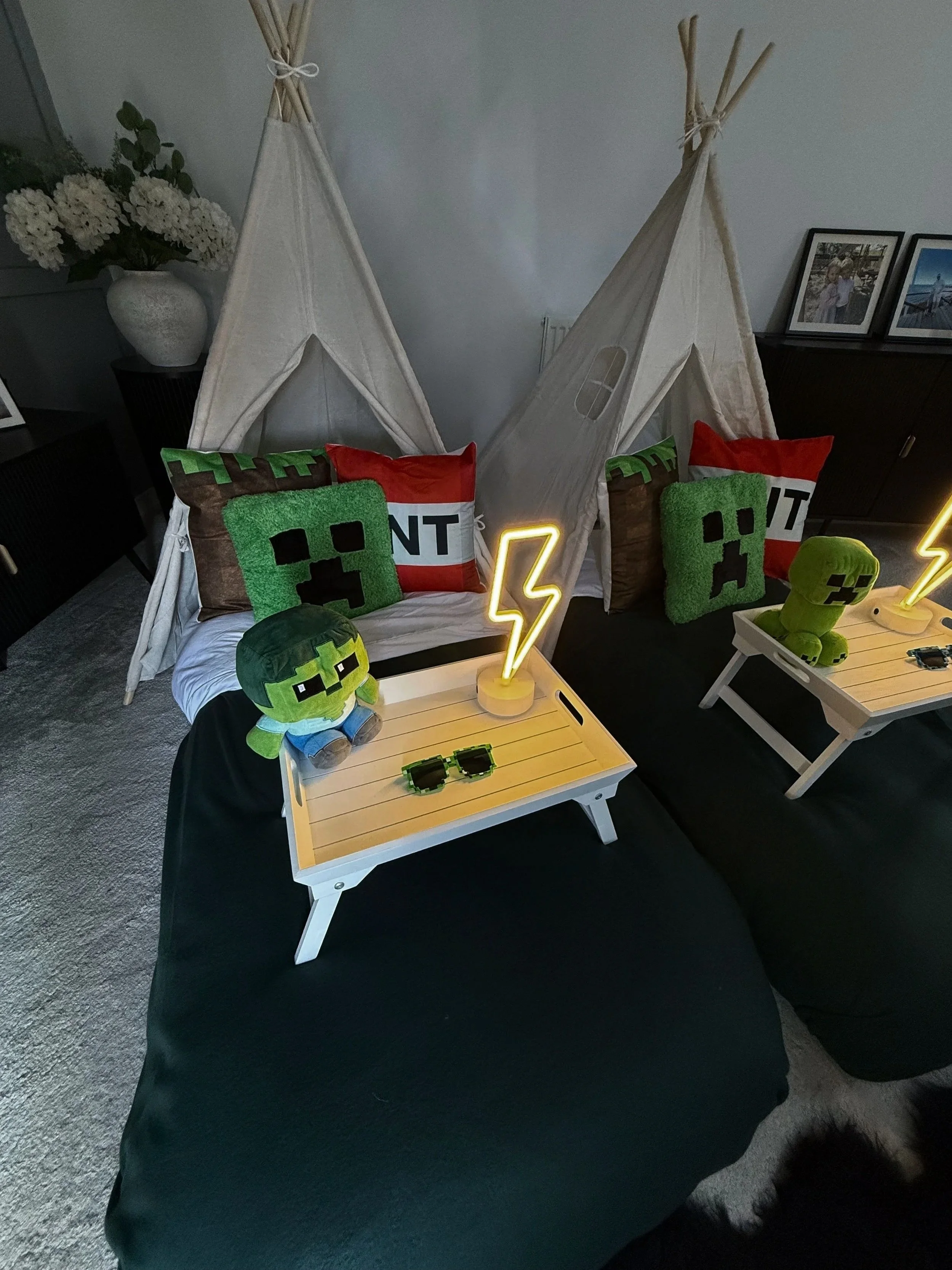 Minecraft Sleepover teepee party by Sweet Dreams Events showing single teepee in evening light with glowing lightning bolt neon lamp, Creeper plushie and pixel sunglasses on breakfast tray for a Minecraft birthday party in Surrey