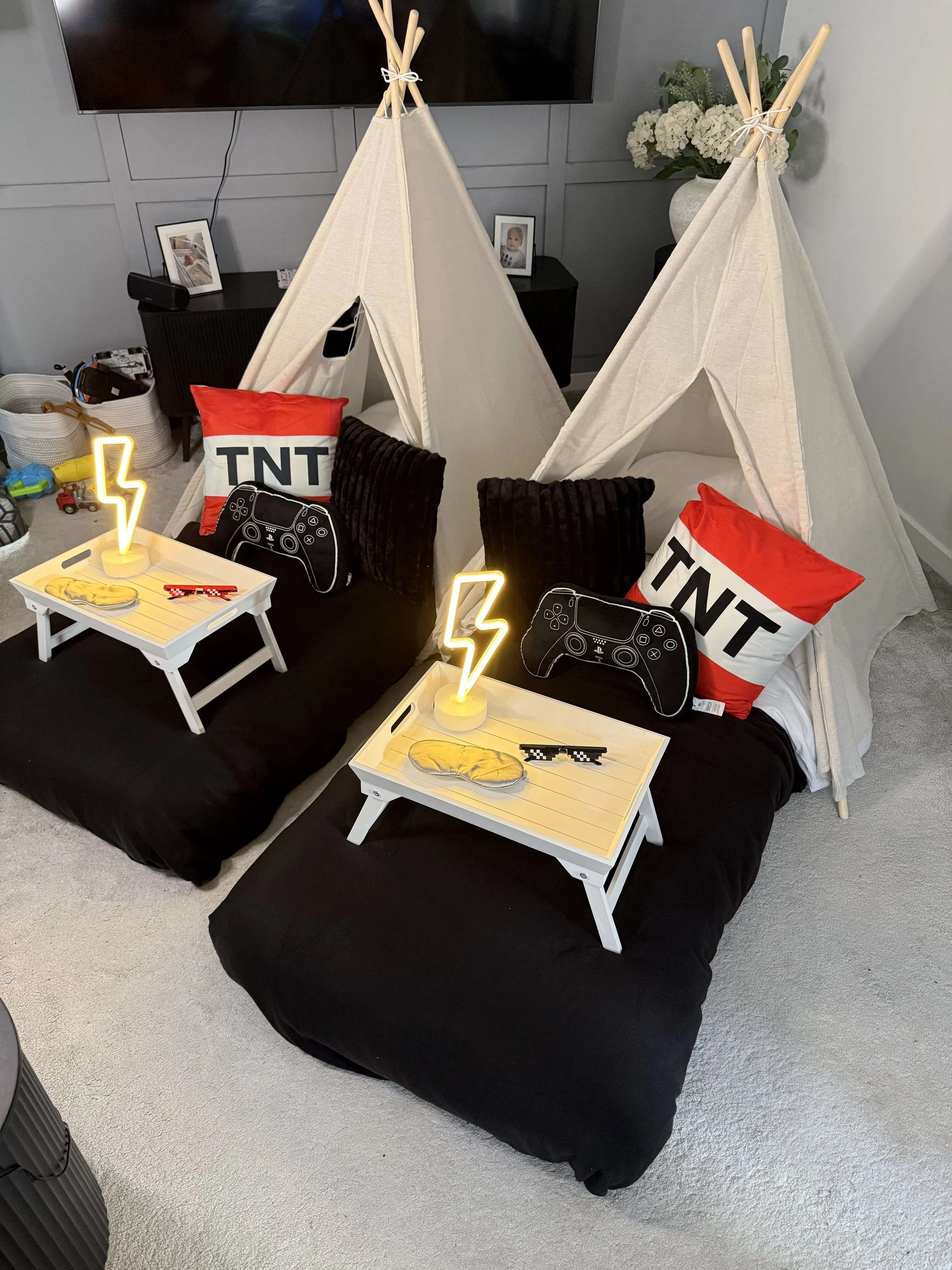 Level Up Lair gaming themed sleepover teepee setup with PlayStation controller pillows, lightning bolt neon lights and pixel sunglasses for a children's gaming party in Surrey