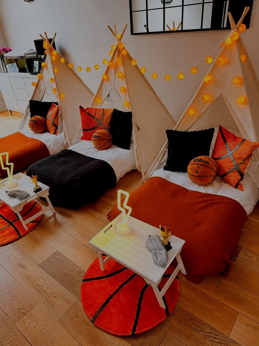 Basketball themed teepee sleepover party hire setup with orange fairy lights, basketball cushions and a gold trophy. Sweet Dreams Events Surrey, Sussex and Hampshire.