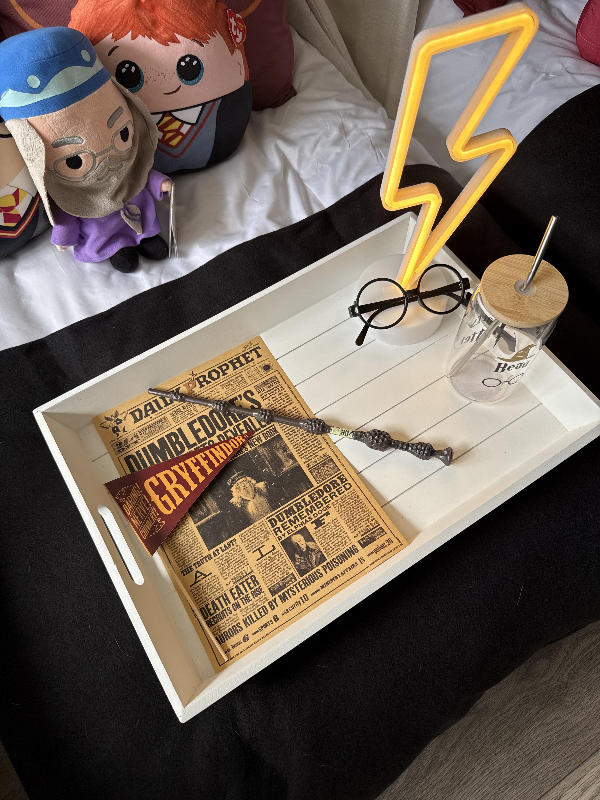 Wizarding Academy themed sleepover tray styled with a wand, round glasses, Daily Prophet newspaper and a Gryffindor pennant beside a personalised Beau cup, part of a luxury teepee sleepover hire setup.