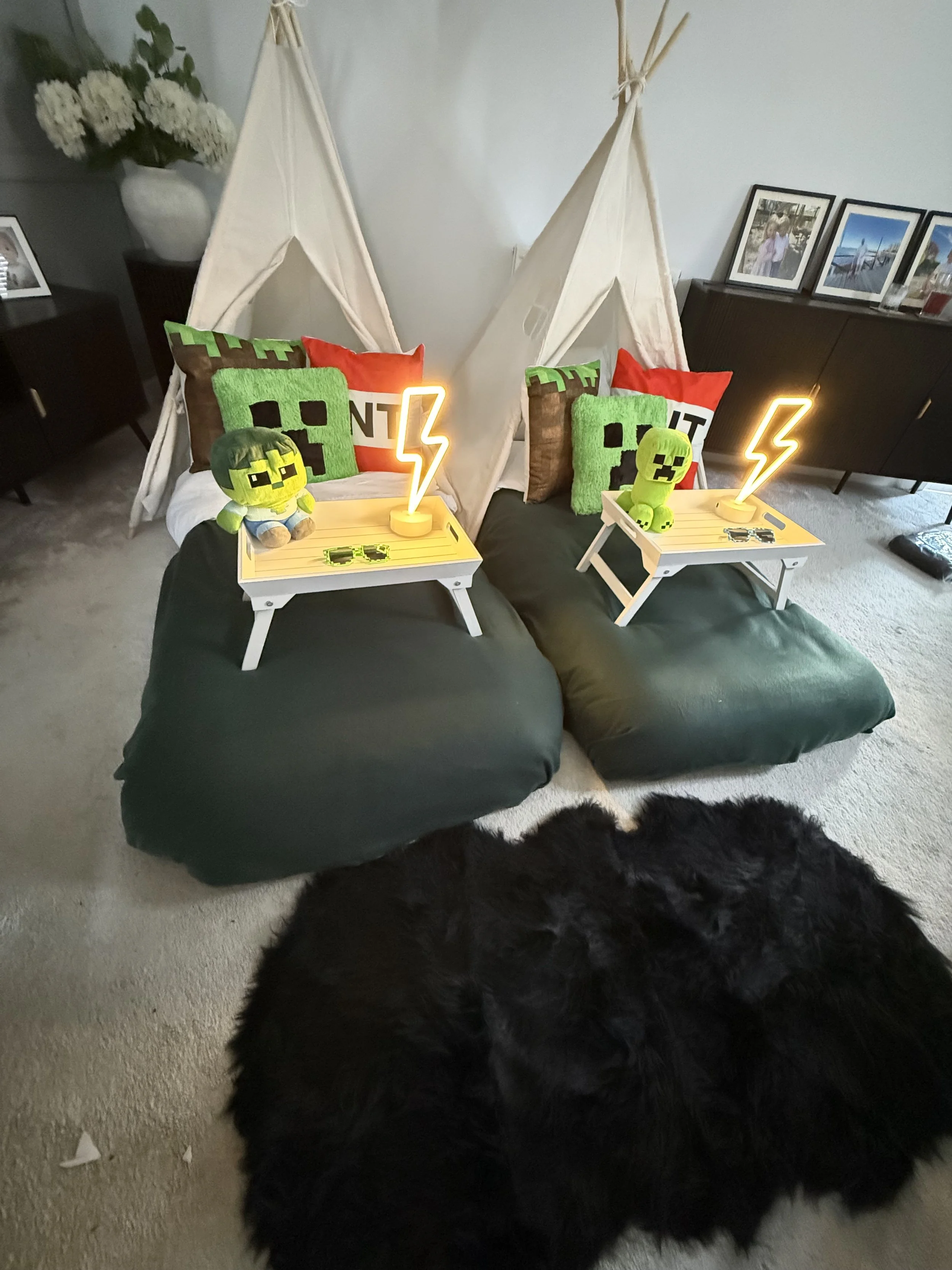 Minecraft Sleepover teepee party by Sweet Dreams Events showing two cream teepees with dark green bedding, Creeper face cushions, TNT props, Minecraft plushies and lightning bolt neon lamps styled for a children's Minecraft birthday party in Surrey