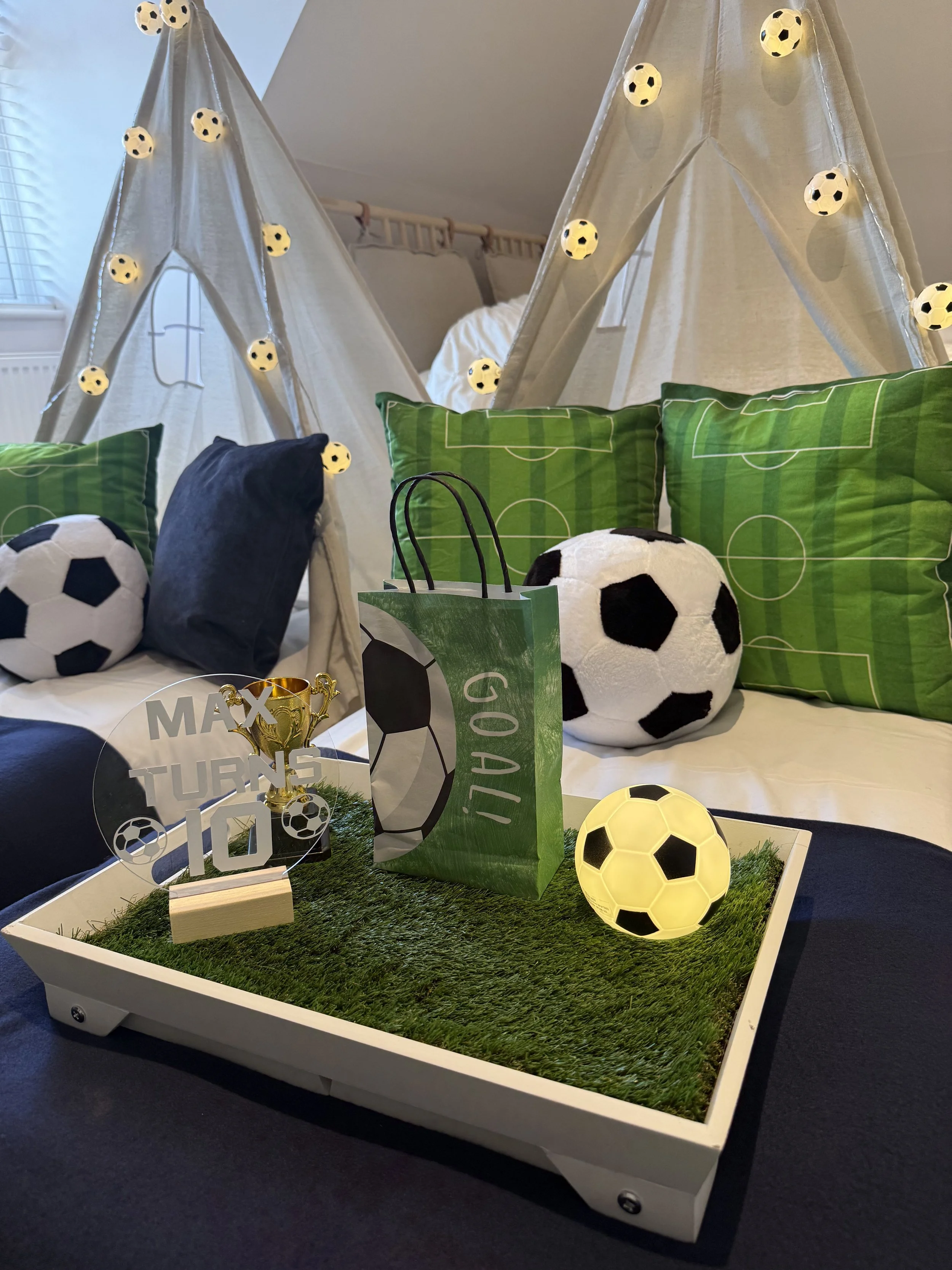 Football themed breakfast trays styled with grass, footballs and a gold trophy at a Match Day Magic teepee sleepover