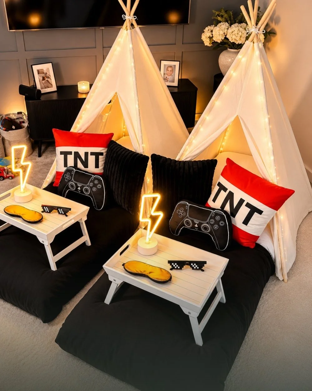 Two fairy lit teepees styled for a gaming sleepover with controller cushions and neon lightning bolts