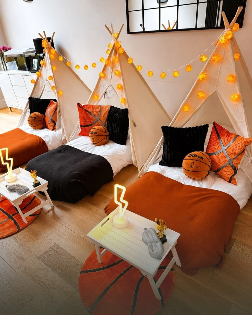 Three teepees styled for a basketball themed sleepover with court colours, basketball lights and trophy trays