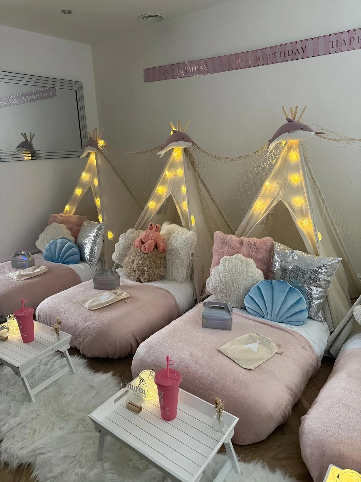 Mermaid Lagoon teepee sleepover party for girls with shell cushions, narwhal toppers, fairy lights, personalised trays and name signs, styled by Sweet Dreams Events in Surrey