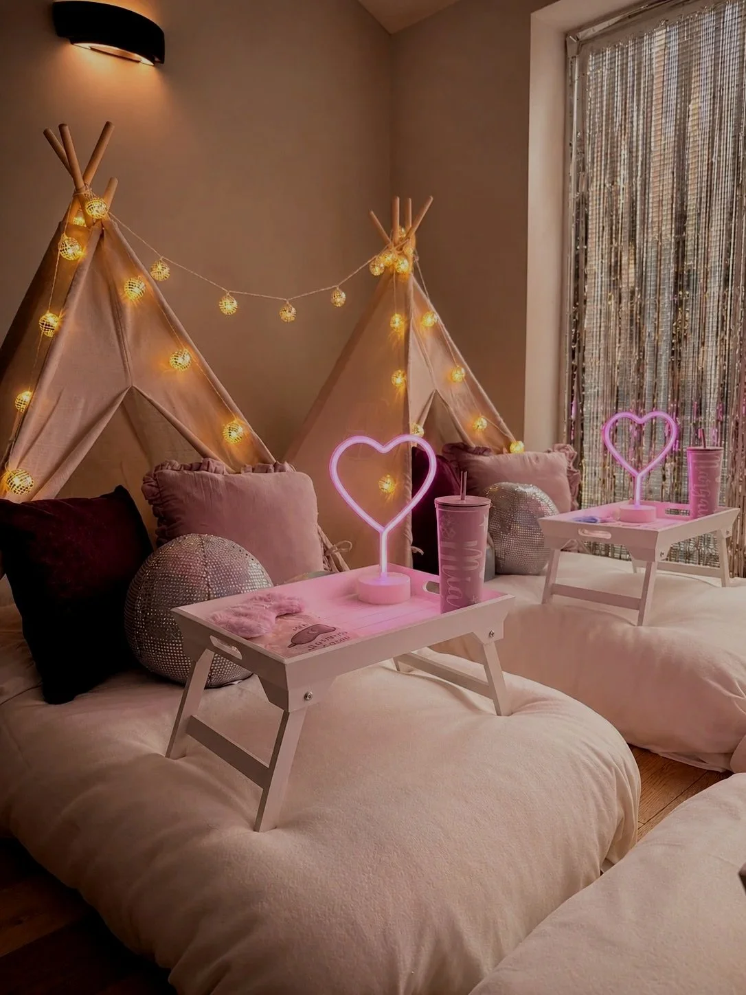 Glitterball Disco Dreams teepee sleepover party by Sweet Dreams Events, showing white breakfast trays with neon heart lamps, personalised cups, sleep masks, disco ball props and silver sequin cushions, styled for a girls sleepover party in Sussex