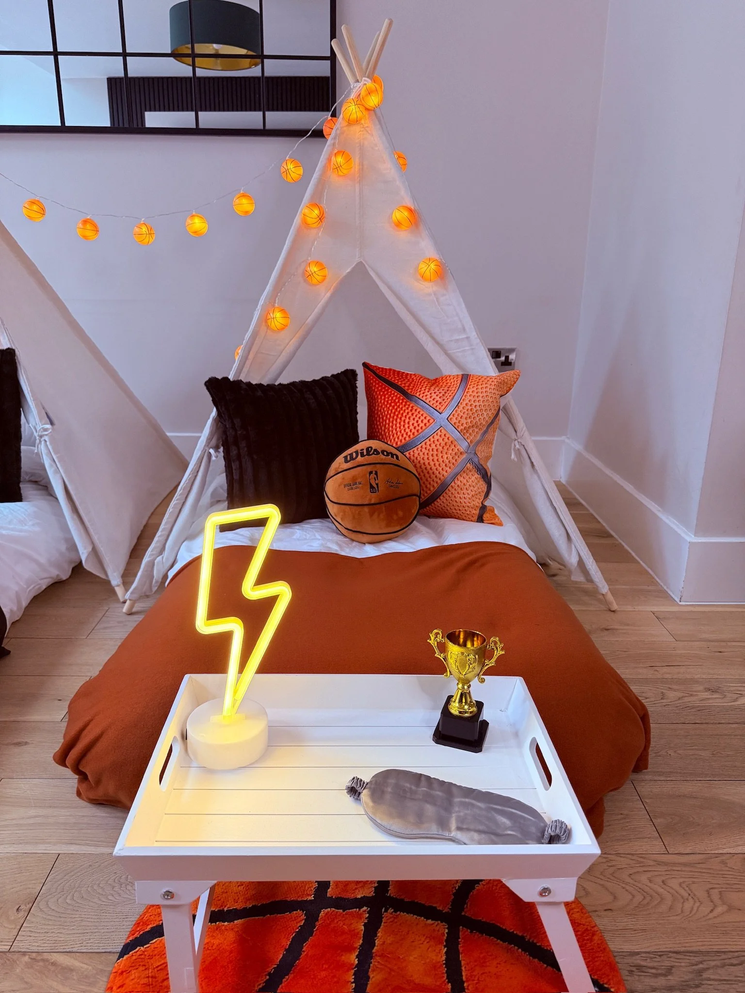 Slam Dunk basketball teepee sleepover with courtside cushions, a Wilson basketball, glowing neon bolt and gold trophy on the tray